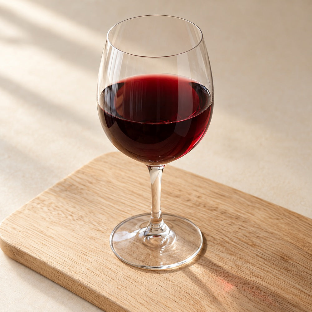 Ein Glas Rotwein auf einem hellen Holzbrett