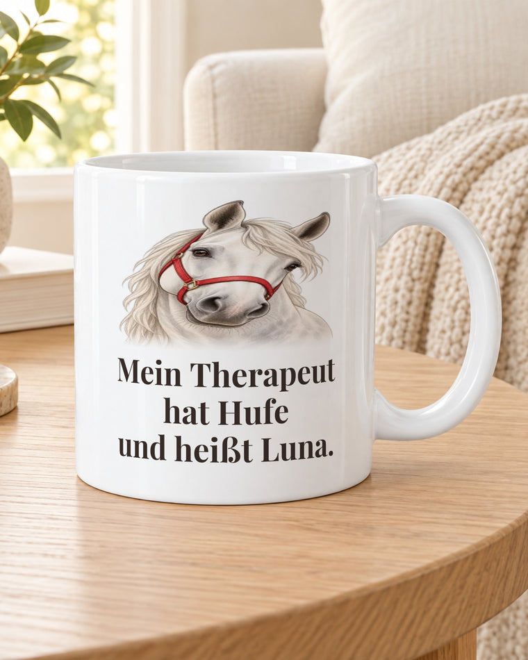 Pferdetasse „Mein Therapeut hat Hufe und heißt Luna.“ auf dem Beistelltisch am Sofa