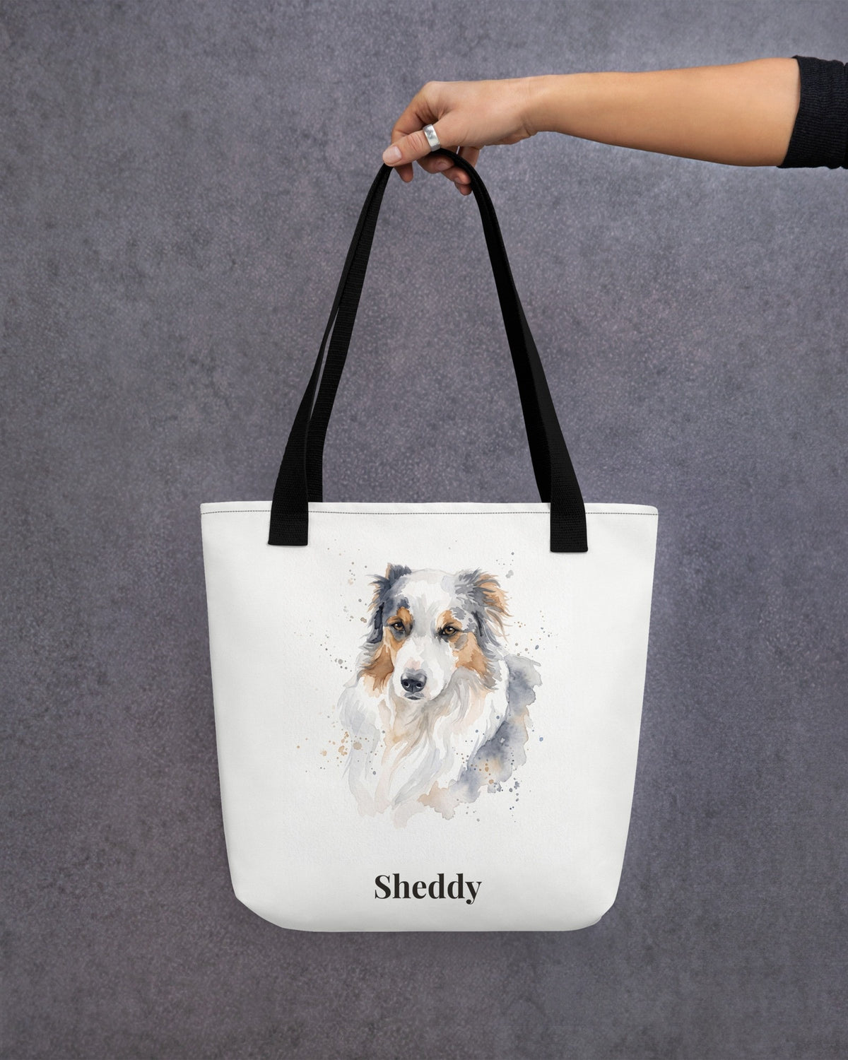 Stofftasche mit Hundeportrait im Aquarell-Stil und Namen Sheddy, von einer Hand getragen