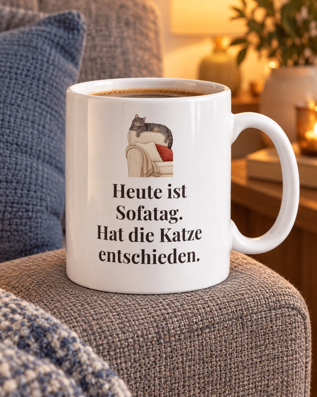 Weiße Keramiktasse Katzentasse mit Spruch: Heute ist Sofatag. Hat die Katze entschieden. auf dem Sofa am Abend