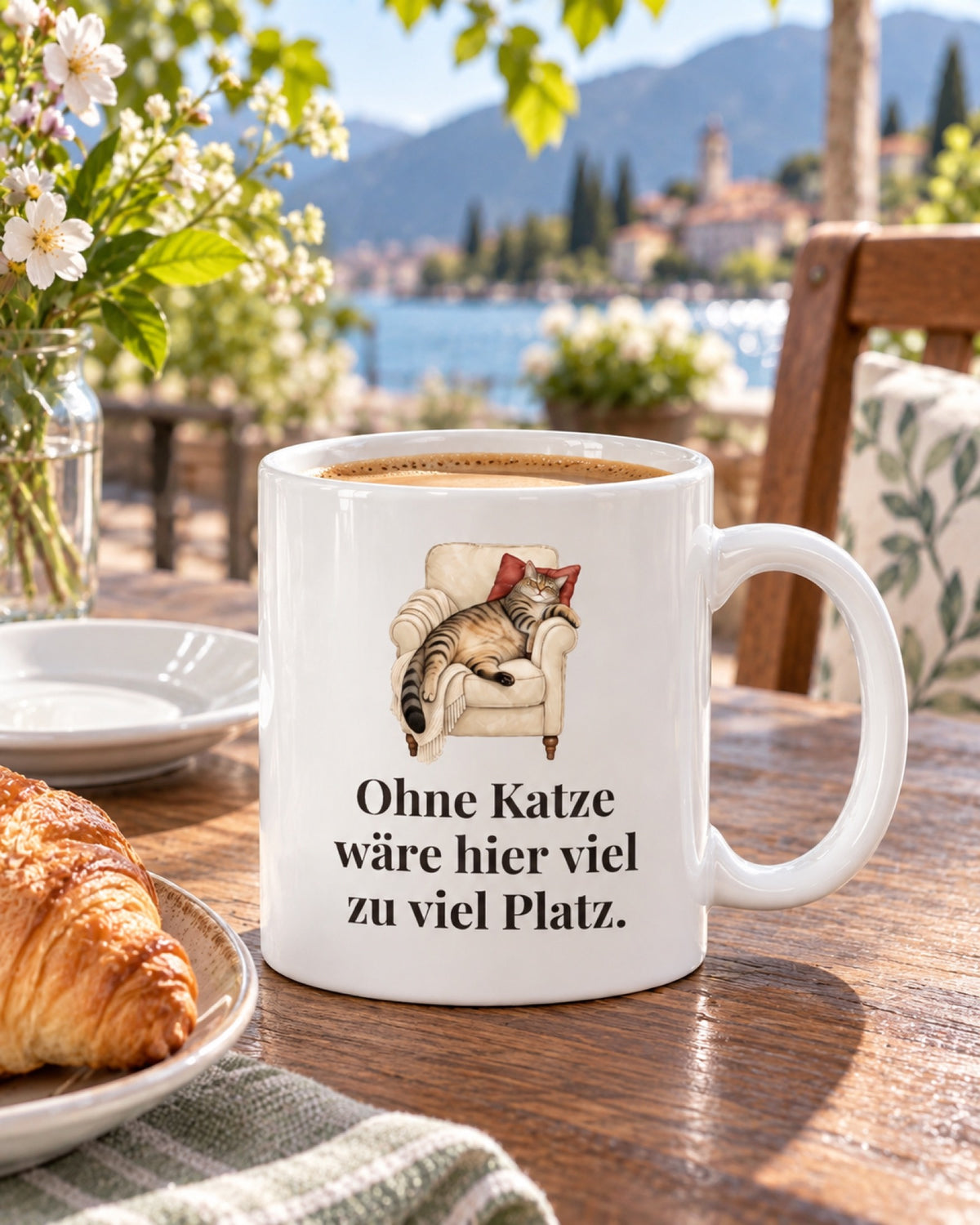 Weiße Keramiktasse Katzentasse mit Spruch: Ohne Katze wäre hier viel zu viel Platz. auf einem Cafétisch im Frühling