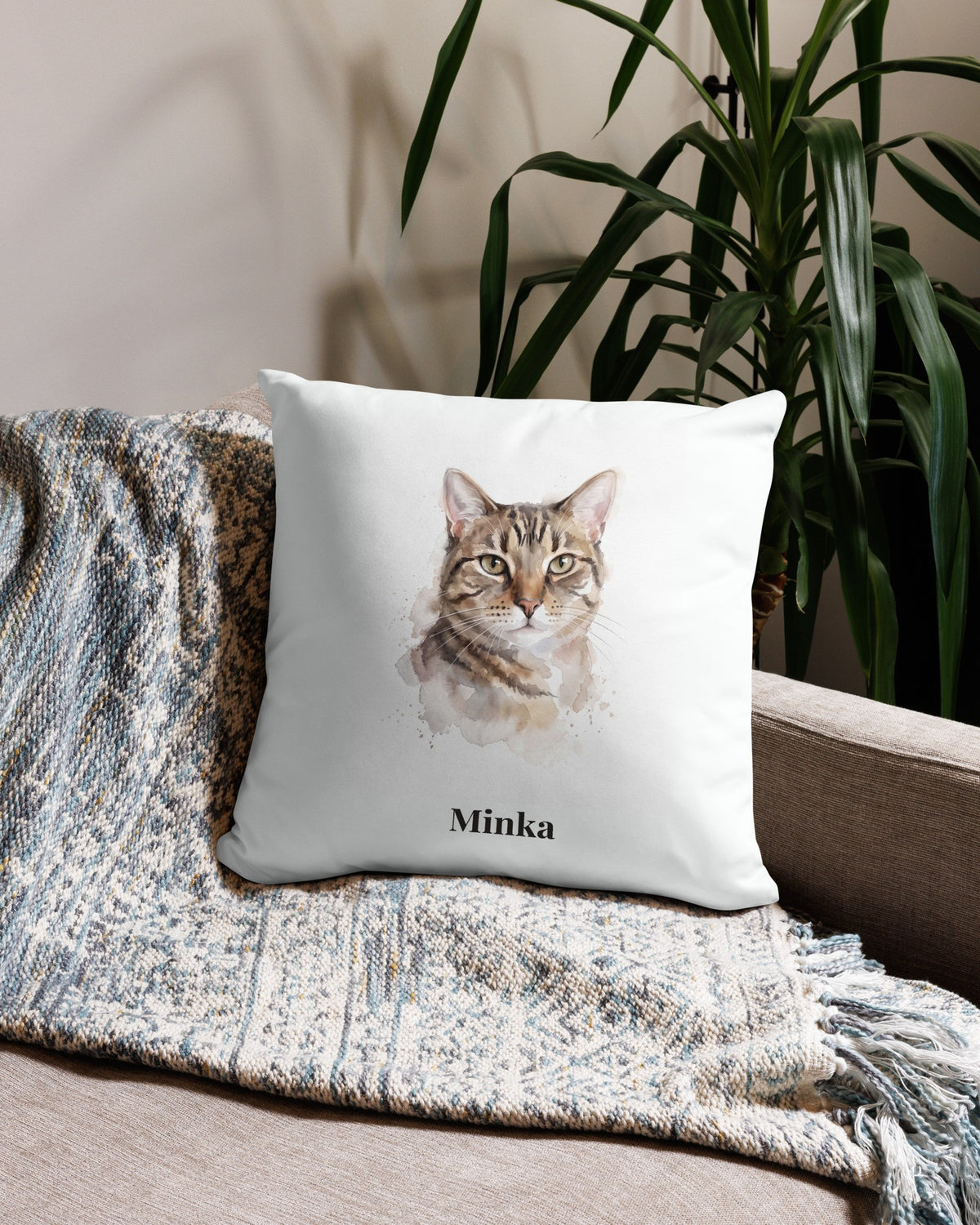 Kissenbezug mit Katzenportrait im Aquarell-Stil und Namen Minka auf dem Sofa
