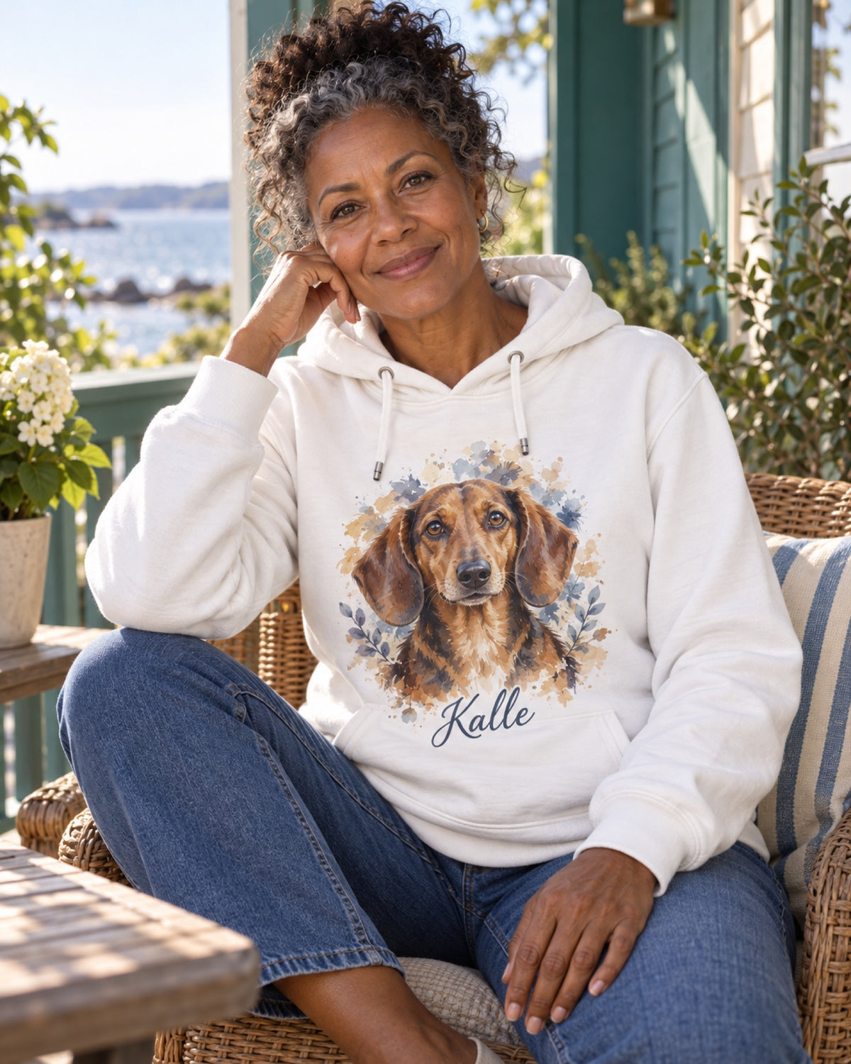 Frau im weißen Hoodie mit Dackel Kalle als Aquarellportrait auf einer maritimen Sommerveranda