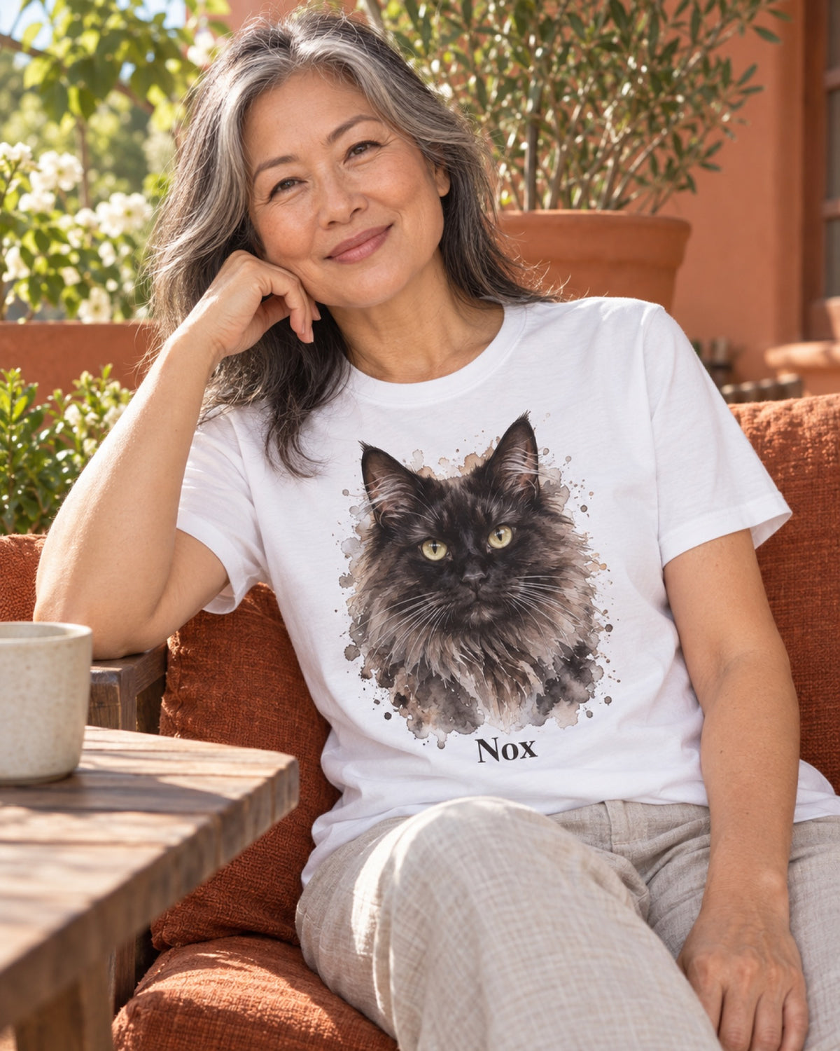 Frau im weißen T-Shirt mit schwarzer Maine Coon Nox als Portrait auf einer rostroten Sommerveranda