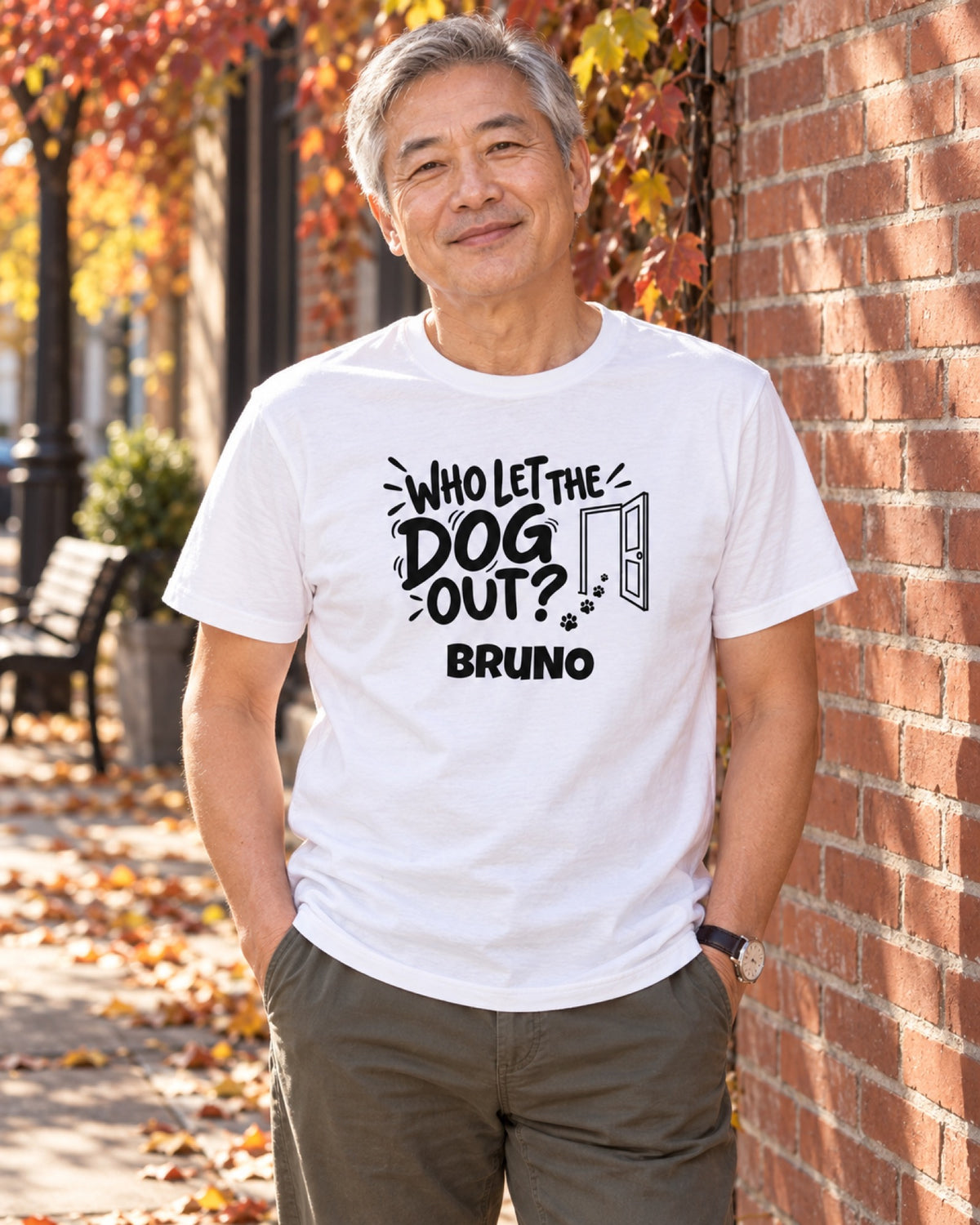 Mann im weißen Who Let The Dog Out T-Shirt mit Beispielname Bruno an einer herbstlichen Backsteinmauer