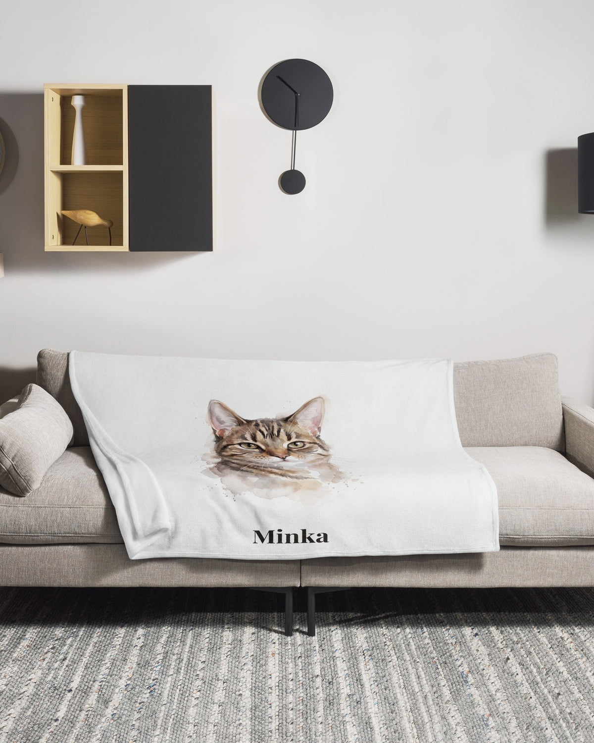 Kuscheldecke mit Katzenportrait im Aquarell-Stil und Namen Minka auf dem Sofa