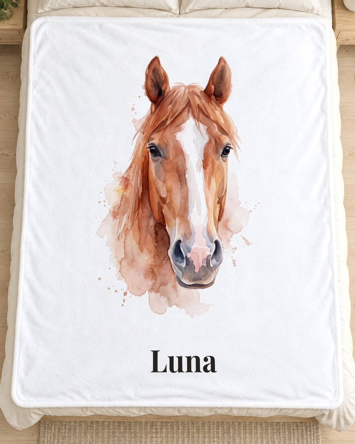 Kuscheldecke mit Pferdeportrait im Aquarell-Stil und Namen Luna auf dem Bett