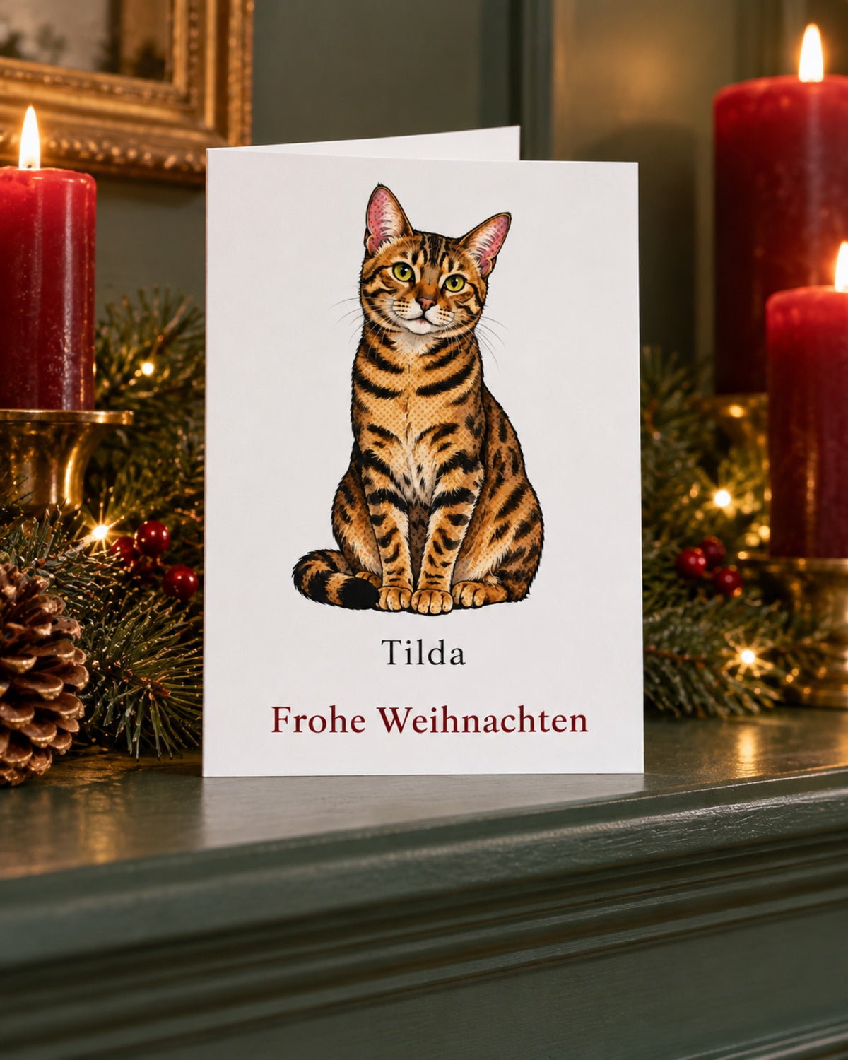 Weihnachtskarte mit Bengalkatze und Namen Tilda auf einem grünen Kaminsims mit dunkelroten Kerzen